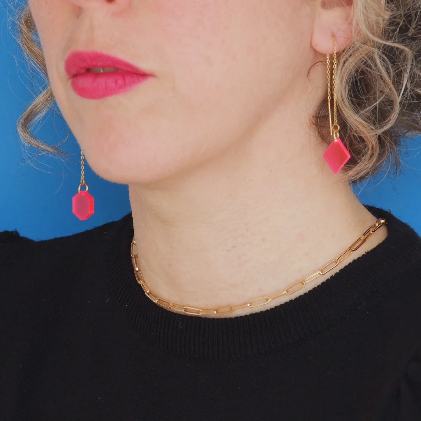 Pendientes colgantes con pieza final rosa sobre modelo lateral