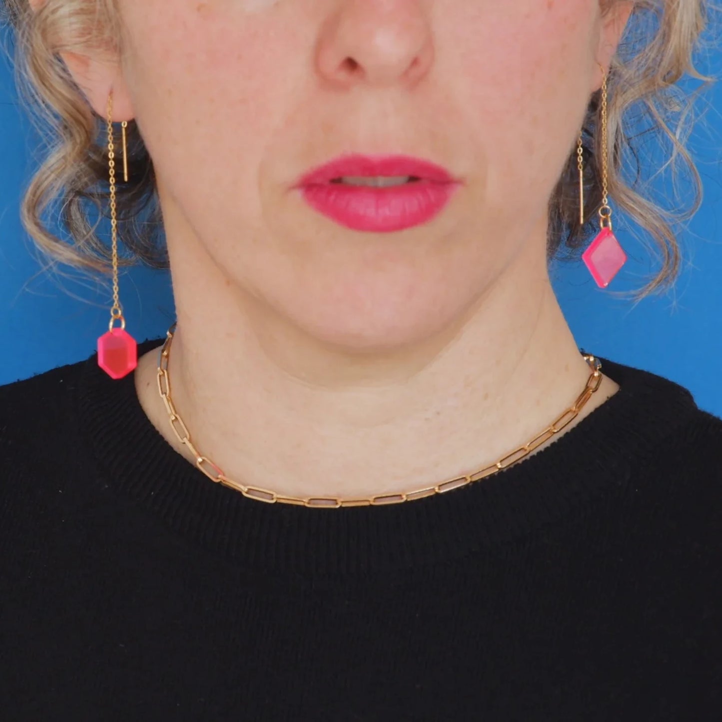 Pendientes colgantes con pieza final rosa sobre modelo frontal