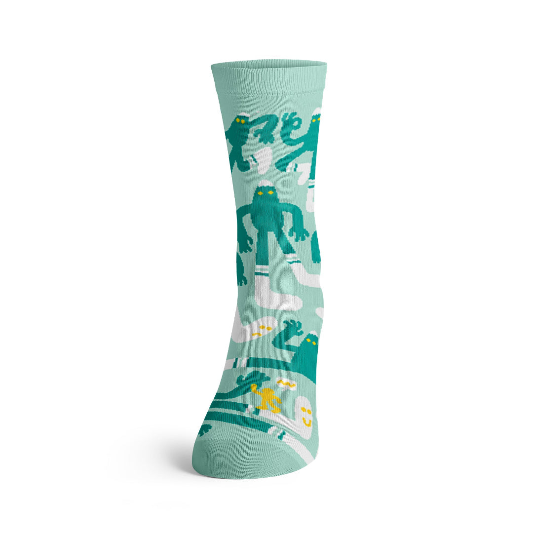 Calcetines Bigsocks de Cha Chá Socks en verde menta con personajes verdes de ojos amarillos y calcetines blancos, vista frontal.