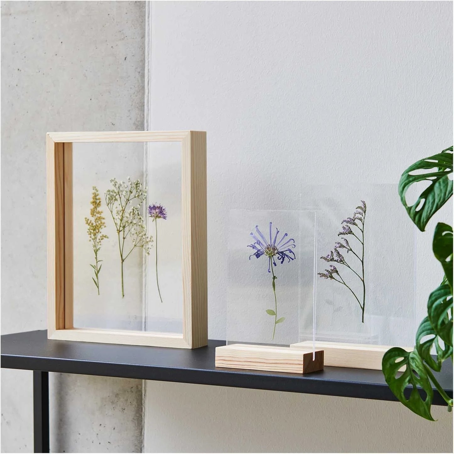 soporte de madera con panel acrílico transparente con la base en color madera colocado sobre una mesa y con flores dentro haciendo un efecto flotante