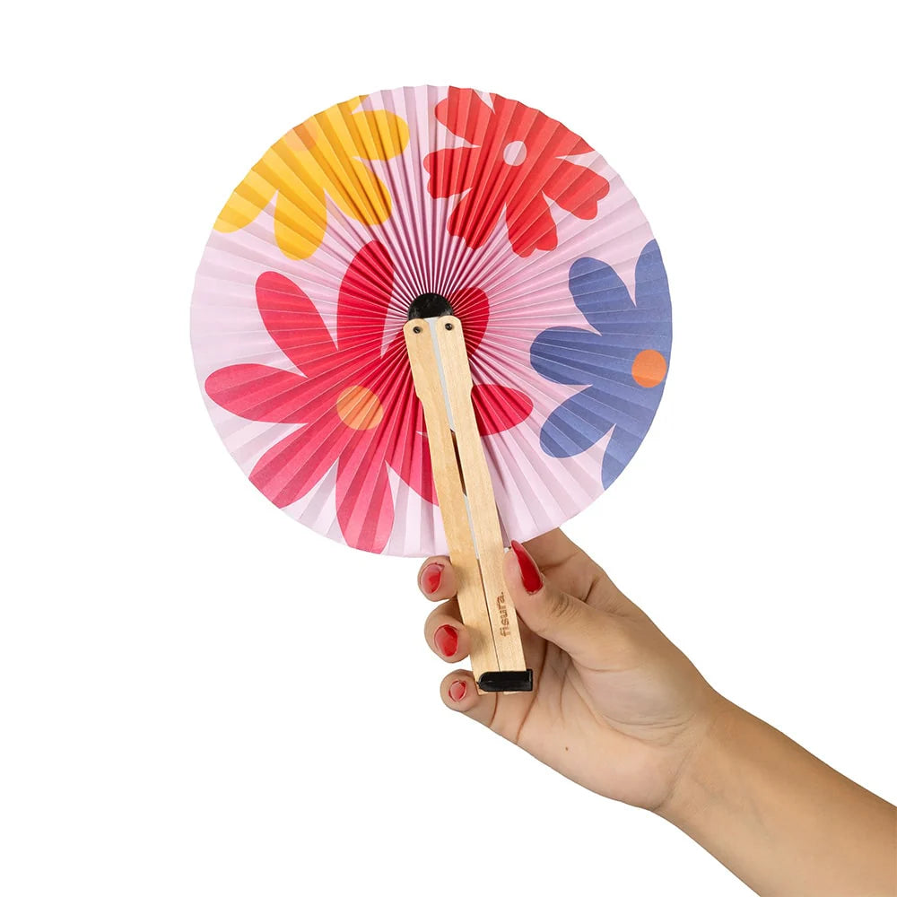 mano sujetando un pai pai de flores de colores rojo, amarillo, azul y rosa, con fondo también rosa
