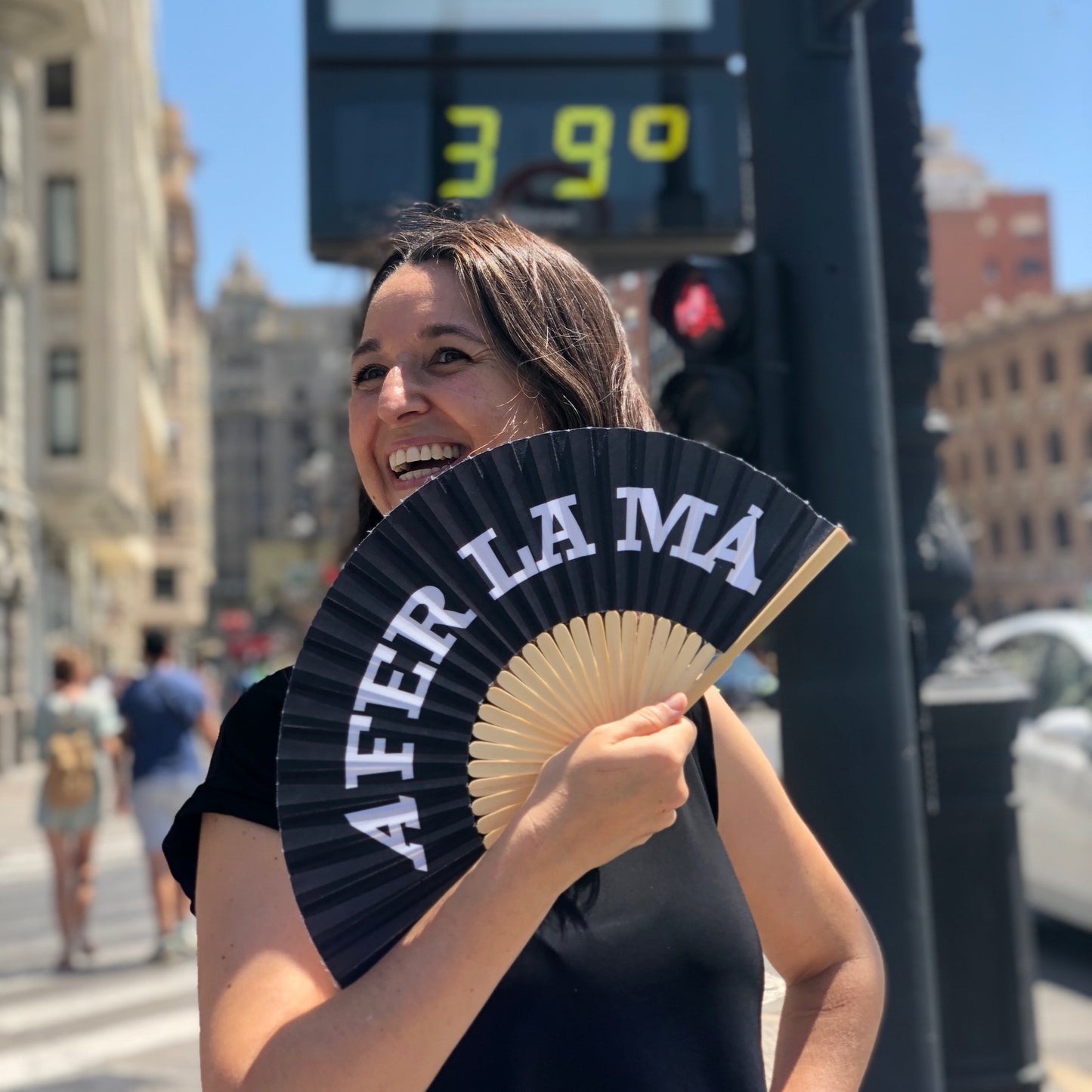 Mujer abanicándose con un abanico negro de A FER LA MÀ en Valencia durante la ola de calor del verano a 39º en el termómetro
