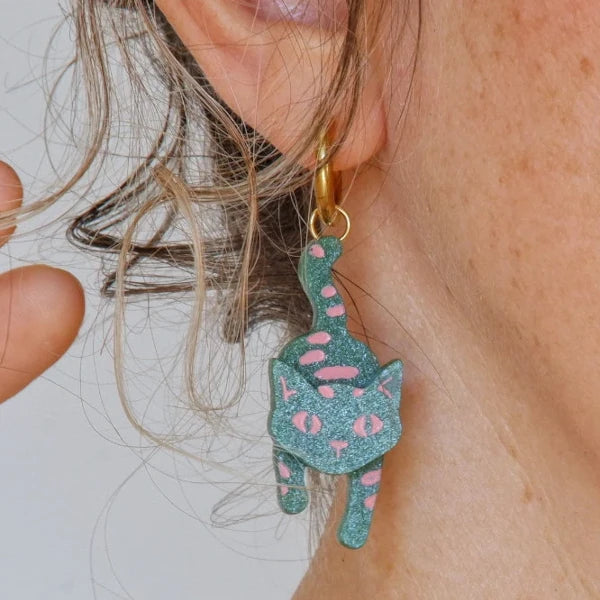 Primer plano de mujer con pendientes de aro con forma de gato en metacrilato verde con detalles en rosa pintados a mano