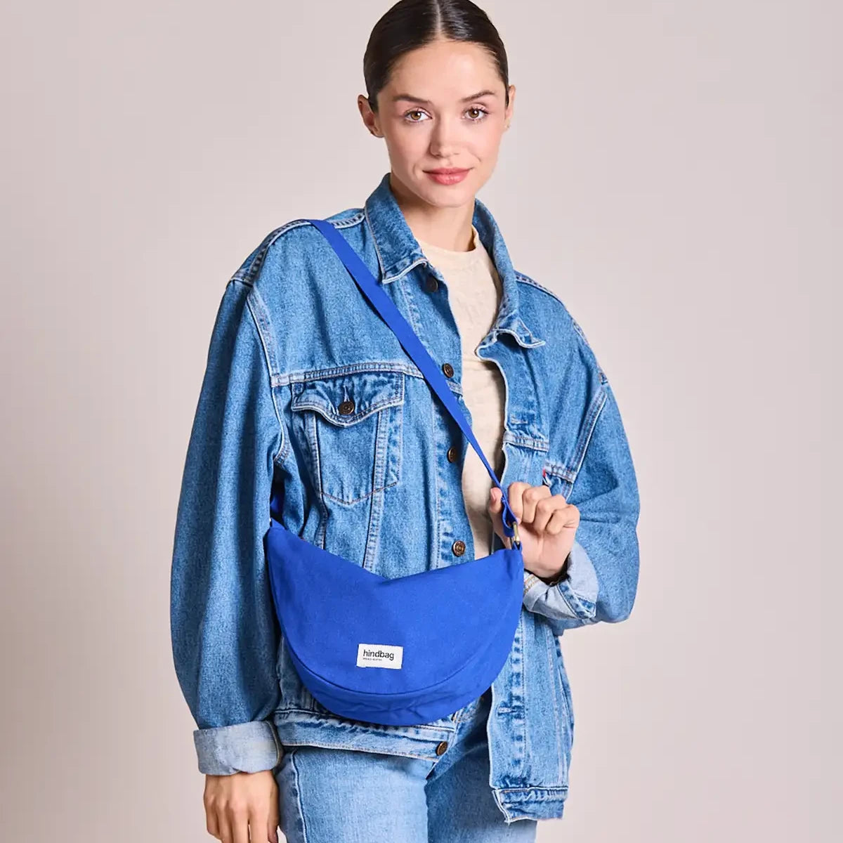 Mujer vestida de vaquero con el bolso riñonera azul eléctrico de la marca francesa Hindbag