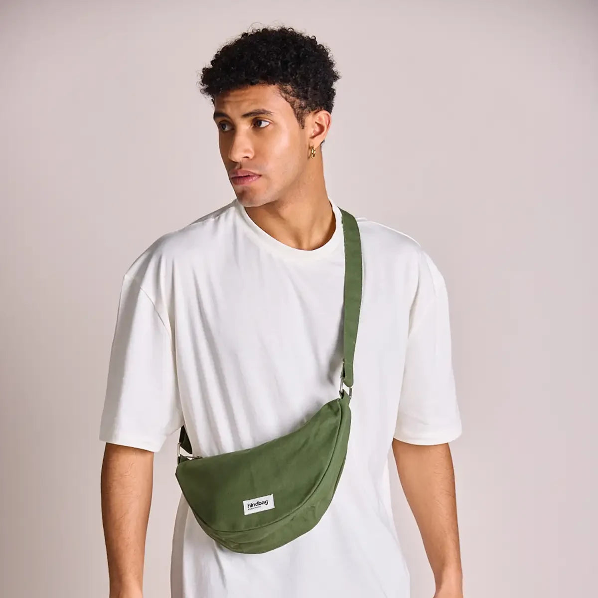 Hombre con camiseta blanca y el bolso riñonera verde oliva de la marca francesa Hindbag