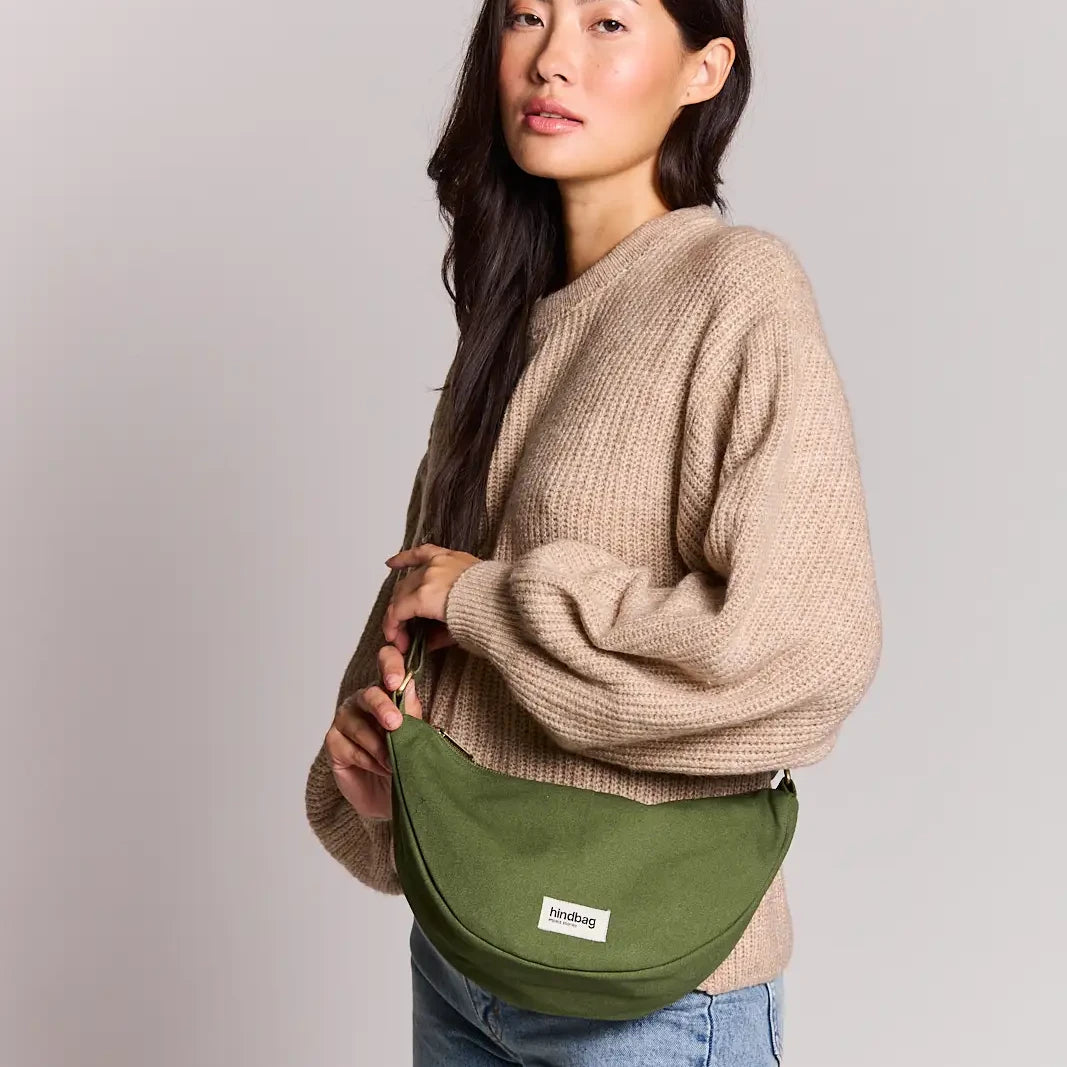 Mujer con jersey de punto beige y el bolso riñonera verde oliva de la marca francesa Hindbag