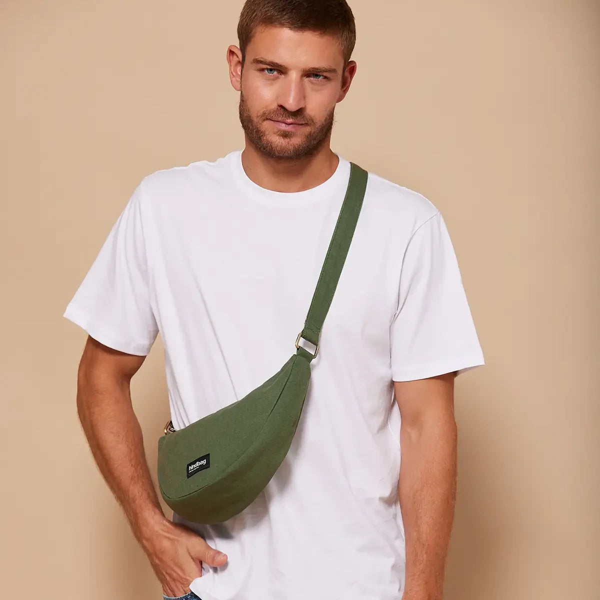 Hombre con camiseta blanca y el bolso riñonera verde oliva de la marca francesa Hindbag