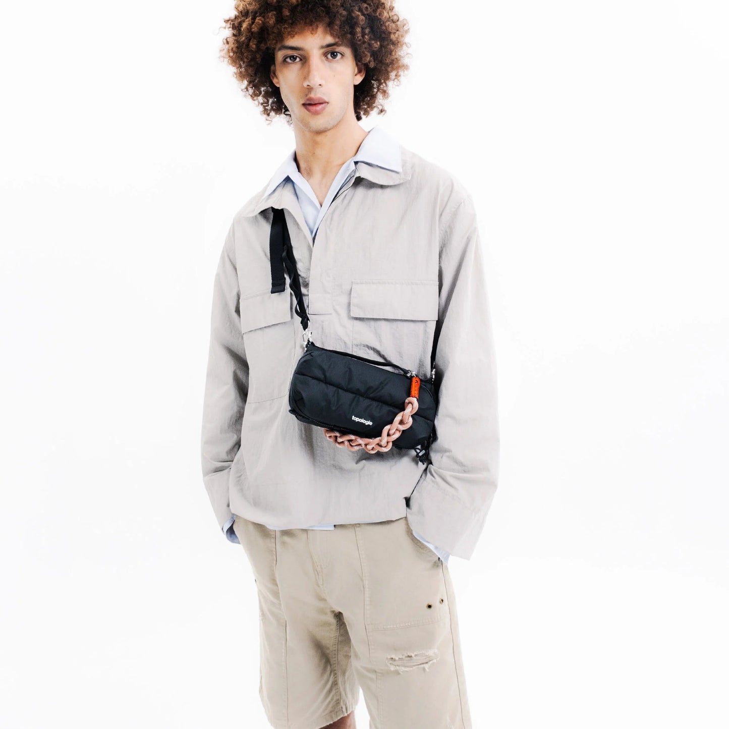 Chico de pelo rizado con el bolso Sacoche de Topologie en color negro