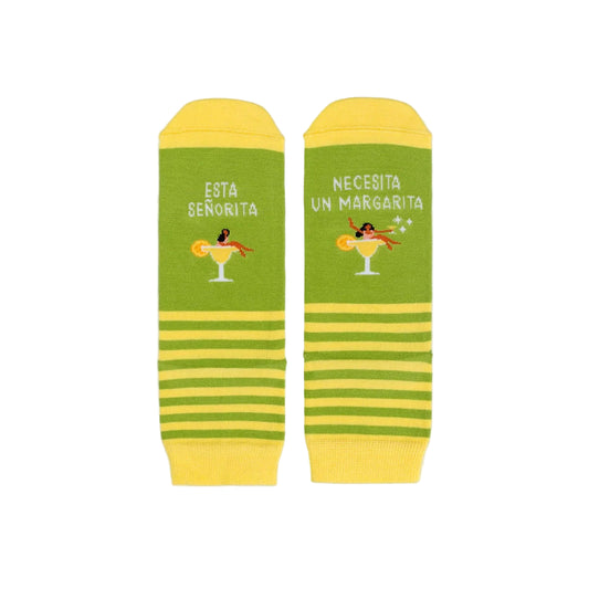 Calcetines cortos verdes y amarillos con el mensaje "Esta señorita / necesita un margarita" y un dibujo de una chica sentada en un cóctel