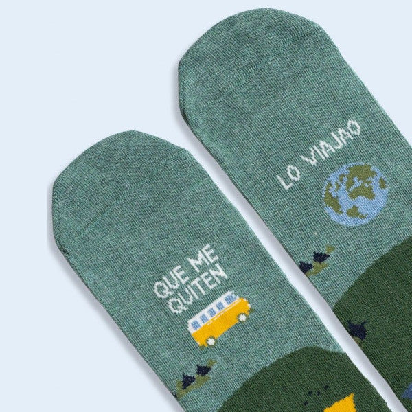 Detalle de las punteras de los calcetines con estampado de montañas tiendas de campaña, una camper y el globo del mundo y el mensaje Que te quiten lo viajao