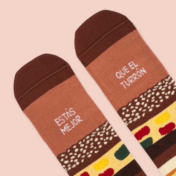 Puntera de los calcetines de Navidad estampados de capas de chocolate, almendra, fruta escarchada, almendrado, turrón blando y el mensaje "Estás mejor que el turrón"