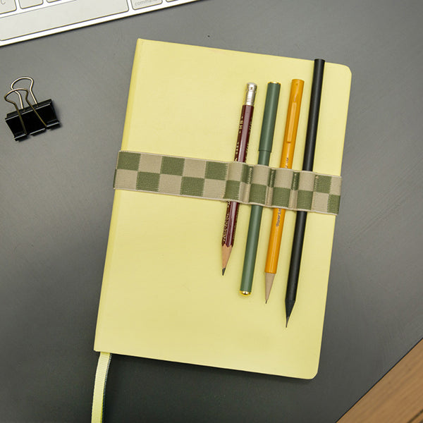 Libreta amarilla con goma elástica para cerrarla con lápices y bolígrafos