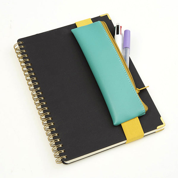 Estuche verde con goma elástica amarilla rodeando una libreta A4