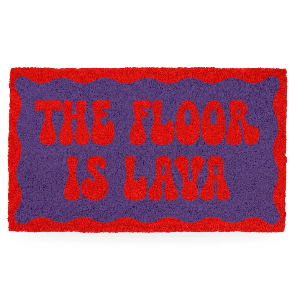 Felpudo rectangular de fibra de coco con el mensaje "THE FLOOR IS LAVA" en letras sesenteras rojas sobre fondo morado