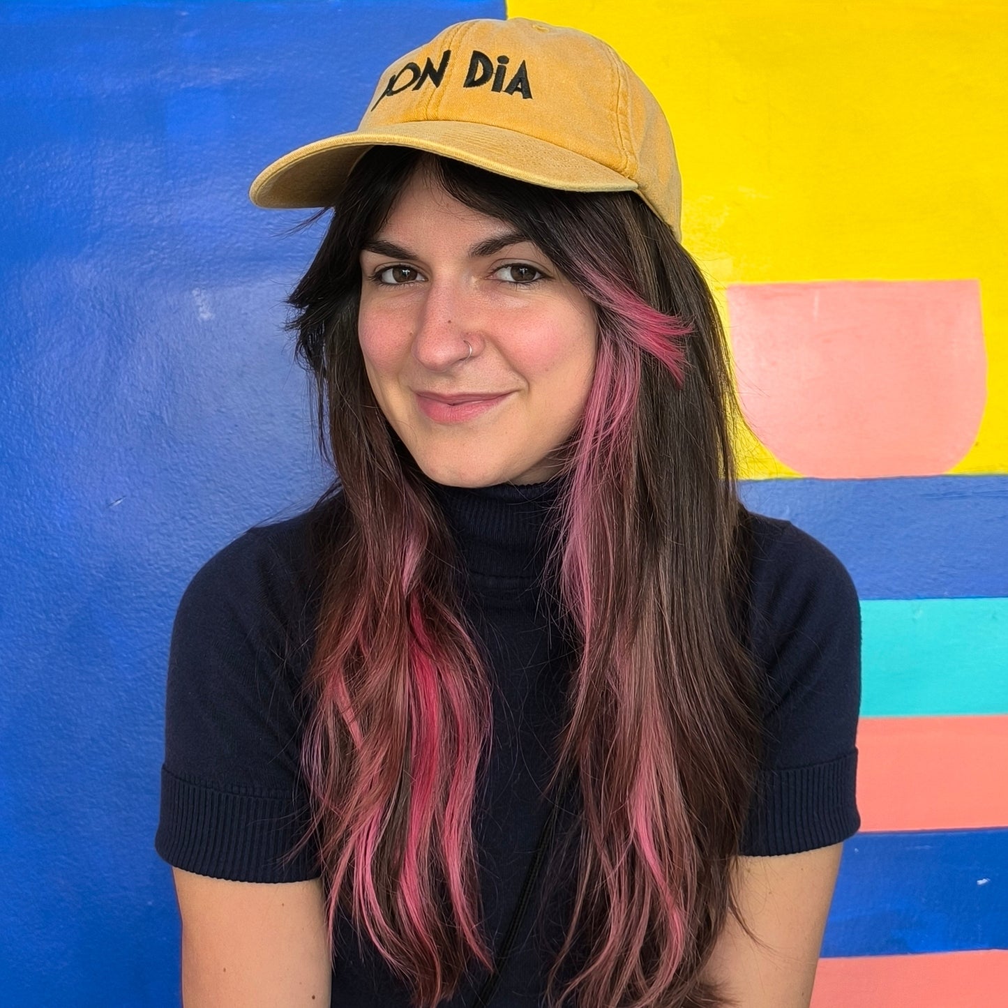 Chica lleva la gorra de Bon dia y sonríe a cámara.