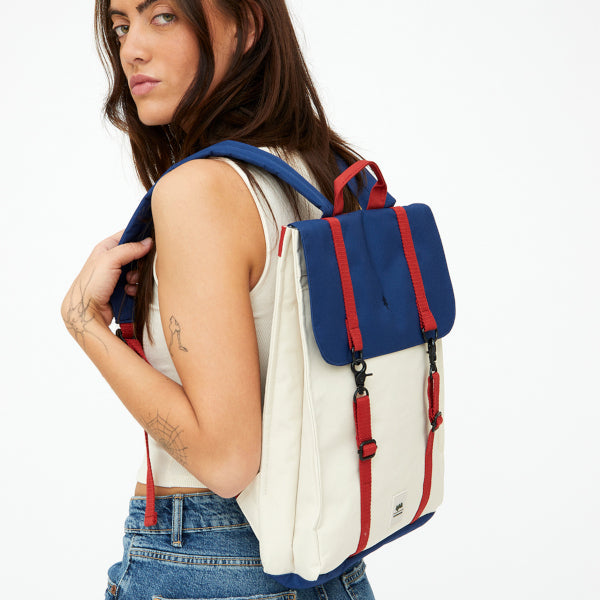 Chica con tatuajes y la mochila Bauhaus de Lefrik en azul marino y crema con correas rojas y cierre con mosquetones 100% reciclada
