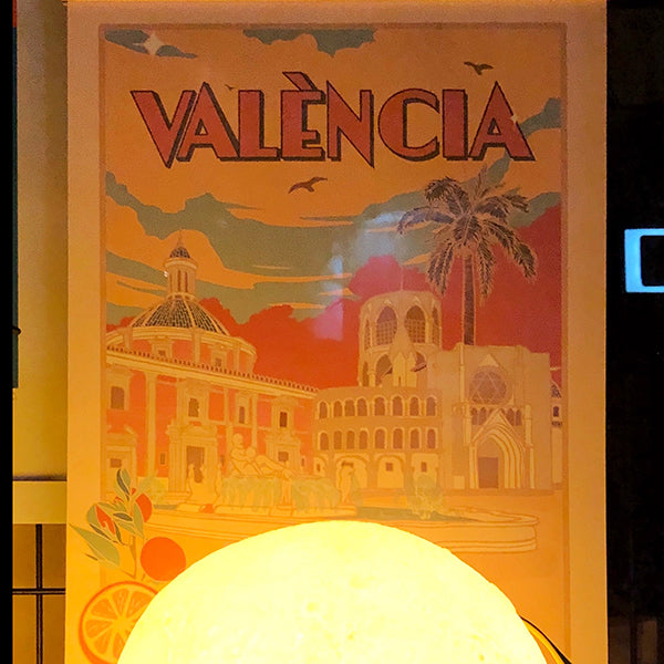 Una ilustración de Vir Palmera en la que se ve la Plaza de la Virgen en Valencia, con la Catedral, la basílica y la fuente; València en grande y unas naranjas en una esquina.