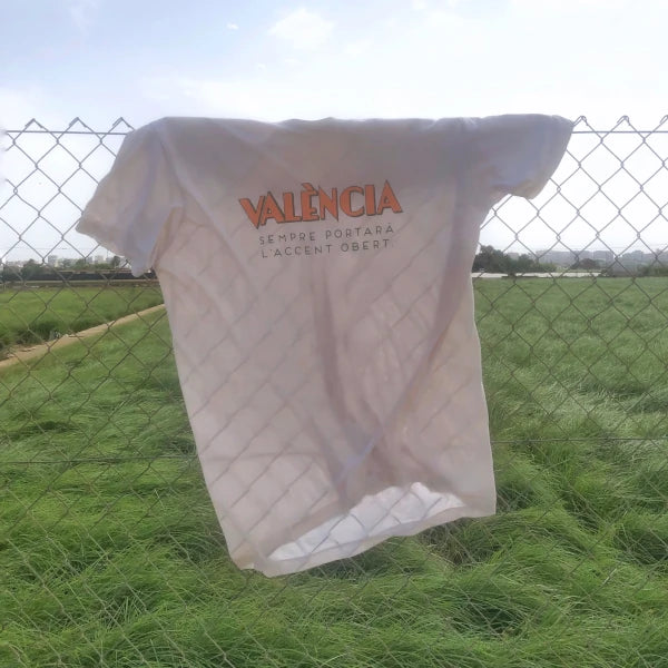 Samarreta reivindicativa en valencià amb la frase "València sempre portarà l'accent obert" de la dissenyadora Vir Palmera penjada sobre una reixa
