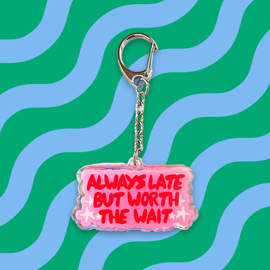 Llavero con el texto Always late but worth the wait en rojo sobre fondo rosa con estrellas