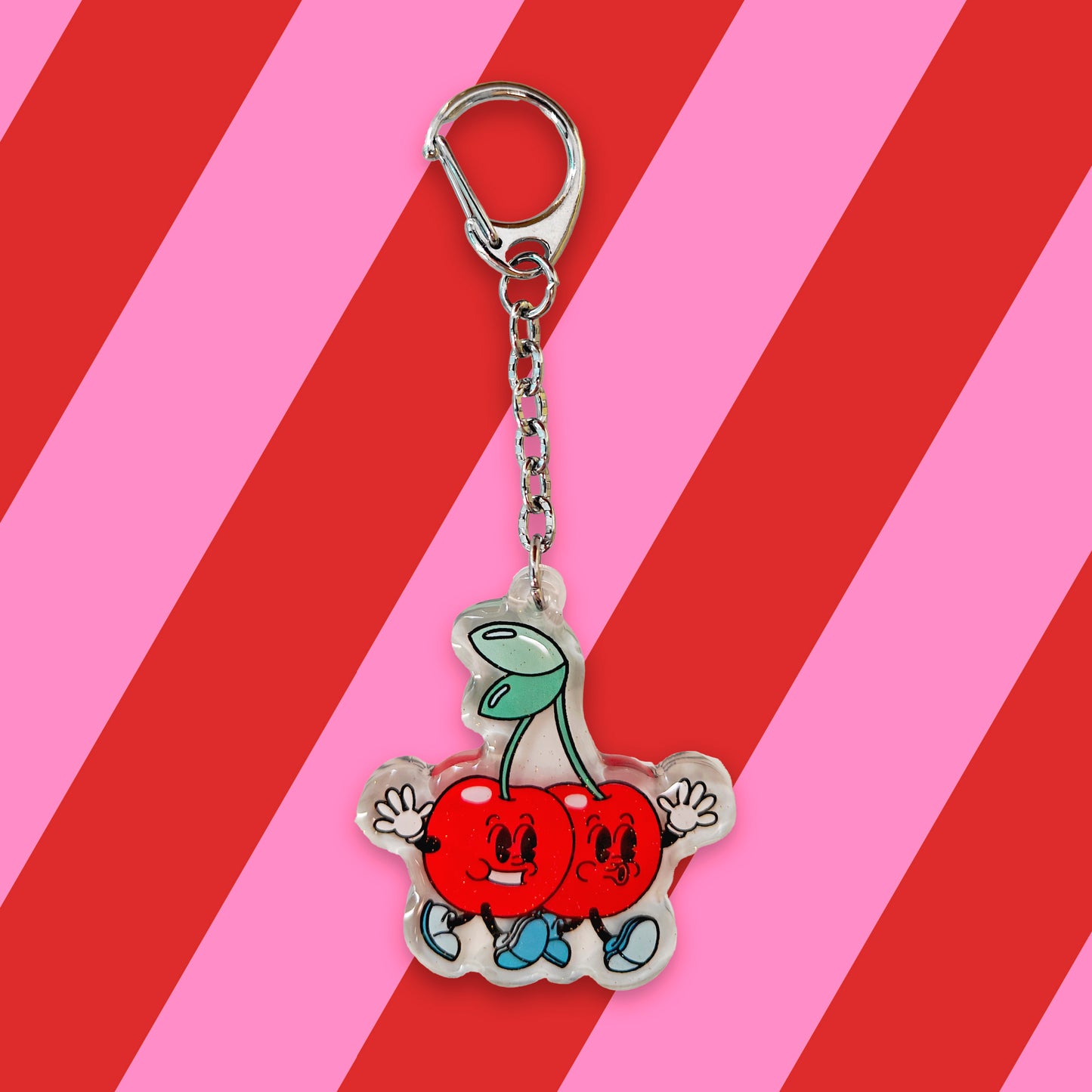 llavero en el que se ven dos cerezas con caritas, piernas y brazos, caminando juntas inseparables como dos buenas amigas