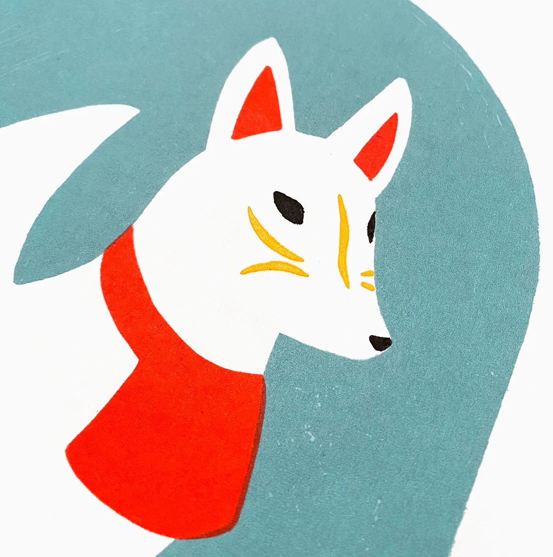 Detalle de Kitsune blanco con detalles amarillos y rojos sobre fondo azul.