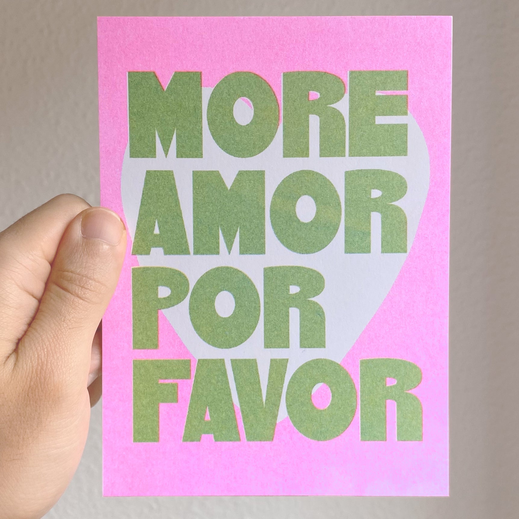 Tarjeta en risografía en verdes y rosas con el mensaje More amor por favor