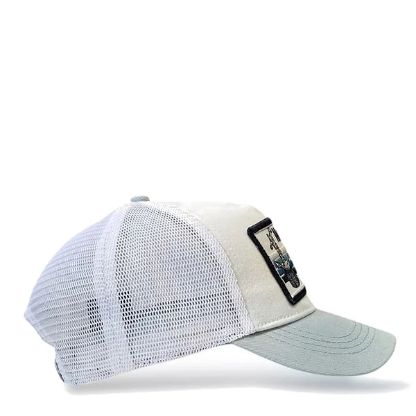Vista lateral de la gorra blanca con visera en azul claro y rejilla blanca con parche de la playa de Mareny Blau, en Valencia