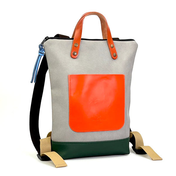Mochila pequeña sostenible de Daniel Chong en color gris con bolsillo delantero de cuero naranja y bajos de cuero verde botella