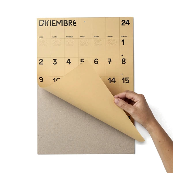 Mano levantando la hoja de diciembre, la última del calendario de pared 2024 en papel marrón y tamaño A3 de Colla Paper