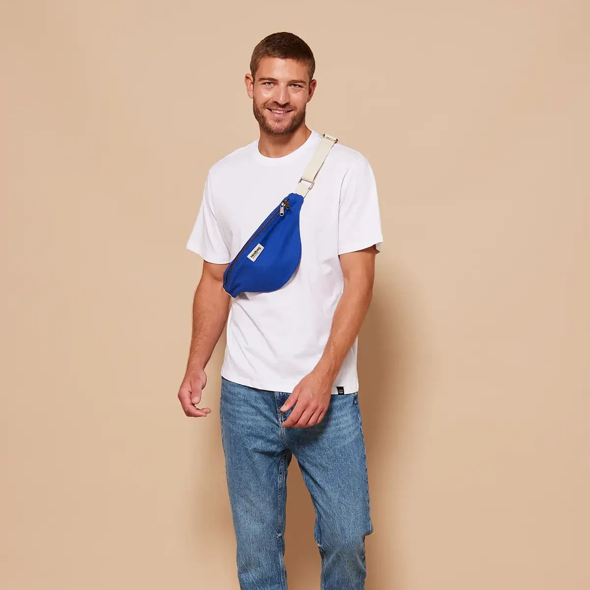 Hombre con camiseta blanca y la riñonera de algodón orgánico en color azul eléctrico de la marca francesa Hindbag cruzada sobre el pecho