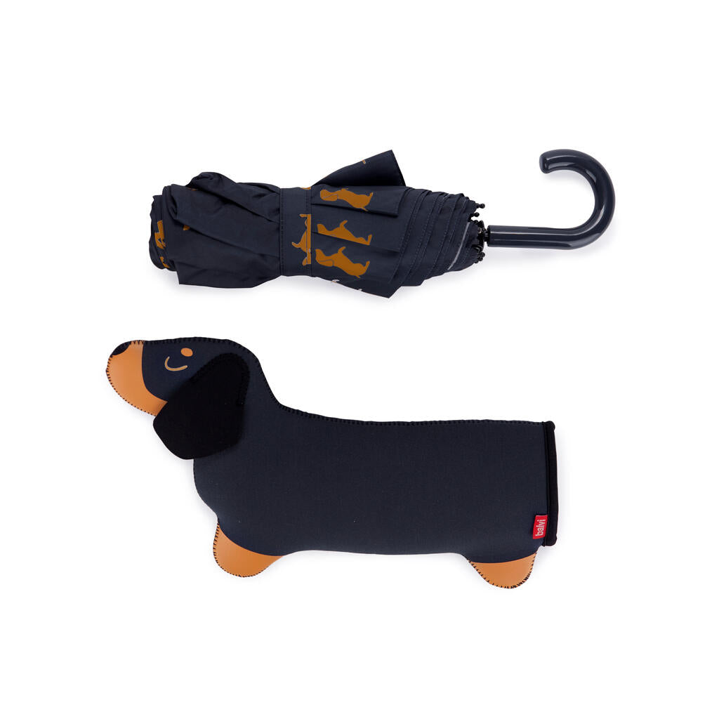 Paraguas plegado con estampado de perros salchicha y mango curvo negro, junto a su funda con forma de perro.