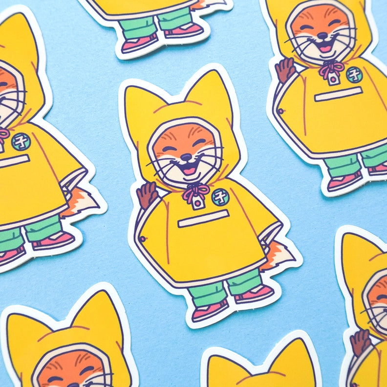 Pegatina de un pequeño zorro con chubasquero amarillo salidando muy contento