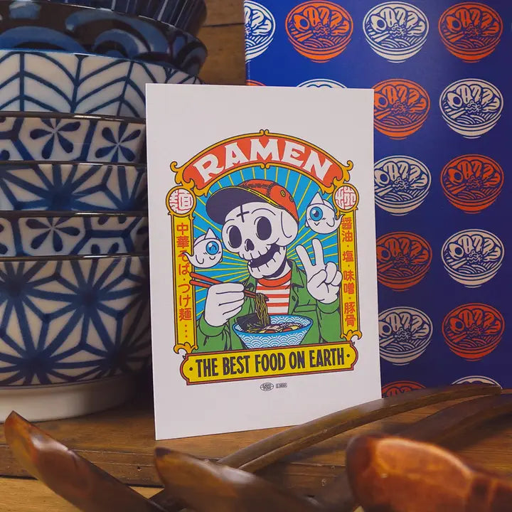 Postal con ilustración de un esqueñeto comiendo ramen sobre unos boles japoneses del estudio Yeaaah!