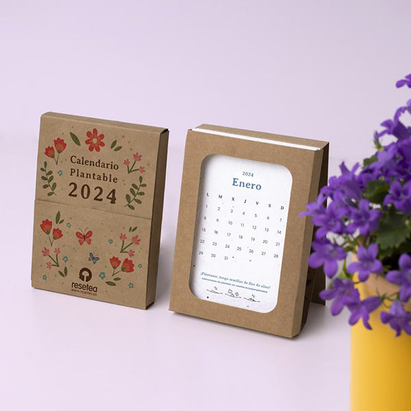 Calendario plantable 2024 con 12 hojas de papel de algodón con semillas en el interior junto a una maceta amarilla con flores moradas