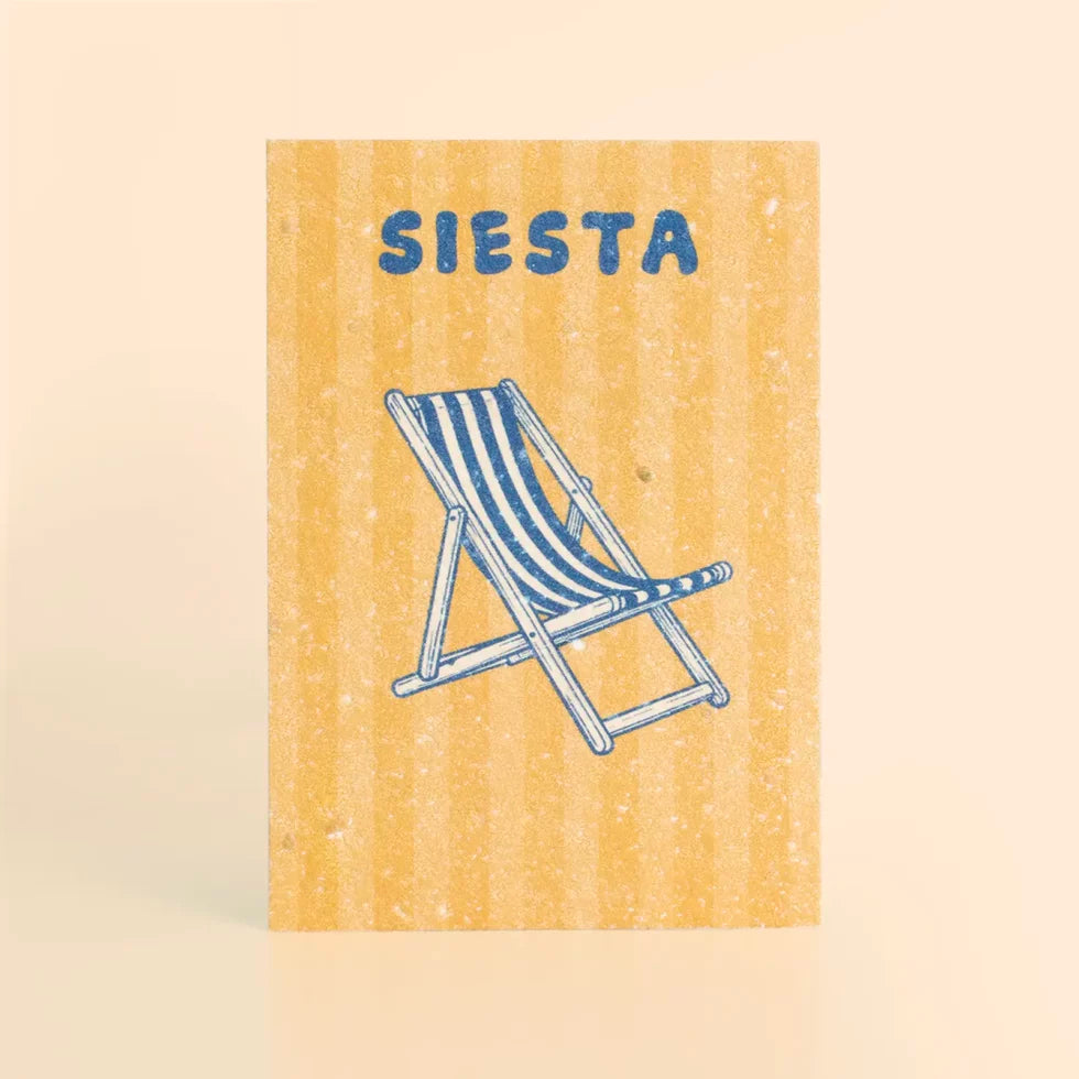 postal con semillas dentro de la marca resetea con el fondo a rayas amarillas, una tumbona a rayas dibujada en azul y el texto SIESTA también en azul