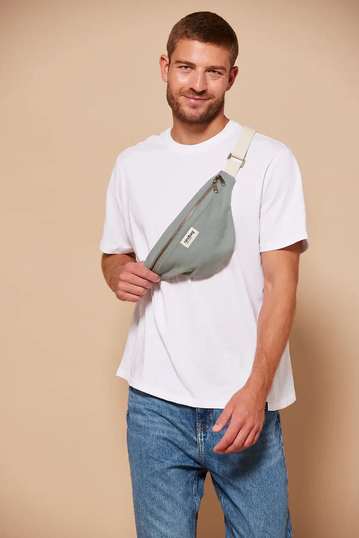Hombre con camiseta blanca con la riñonera de la marca francesa Hindbag color azul verdoso salvia y correa blanca