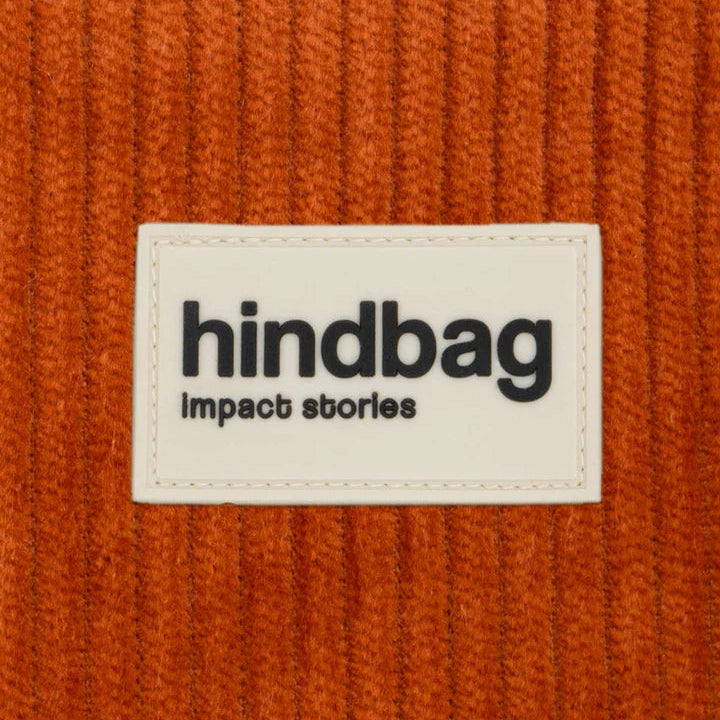 Detalle del tejido y la etiqueta de la marca Hindbag del bolso de pana de color rojo ladrillo