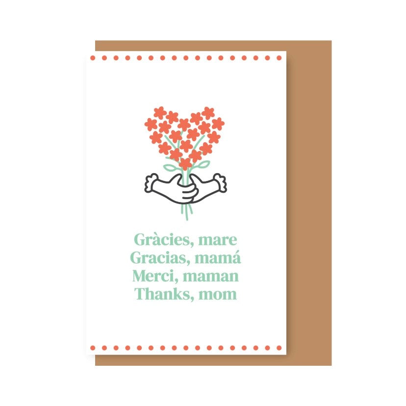 Tarjeta ilustrada con flores rojas en forma de corazón sujetadas por unas manos. Debajo se lee "Gràcies, mare. Gracias, mamá. Merci, maman. Thanks, mom" en diferentes idiomas, sobre fondo blanco con una cenefa de puntos rojos arriba y abajo. Detrás, un sobre de color kraft.