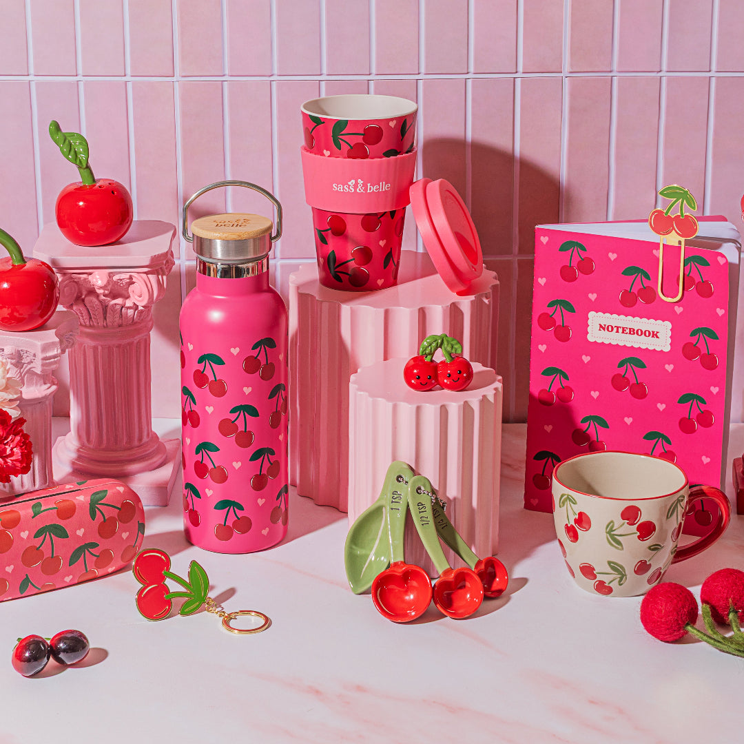 Token de cerezas sonrientes con muchos productos de cerezas de tonos rojos y rosas alrededor.