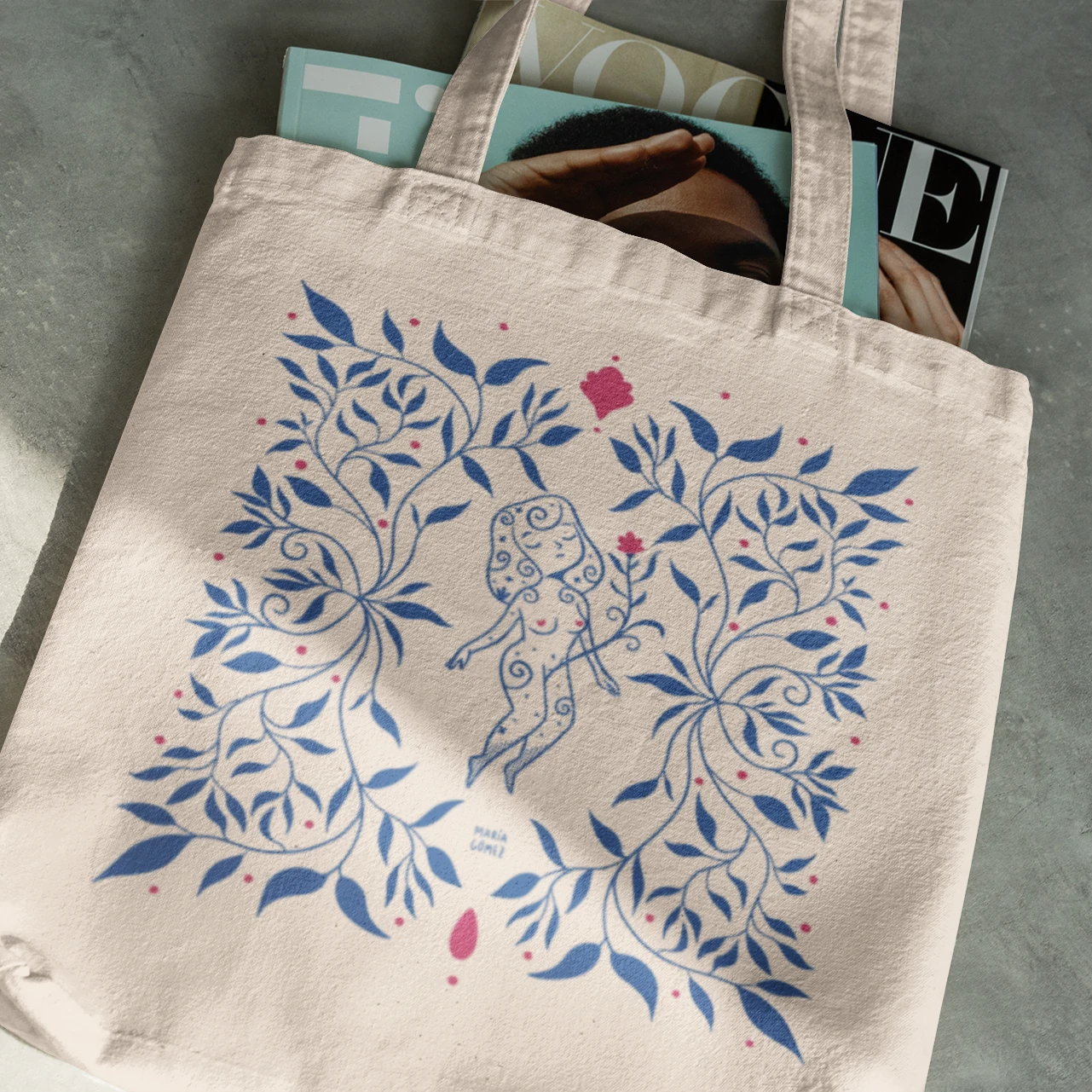Bolsa de tela con una mujer flotando entre flores azules de María Gómez llena de revistas Vogue