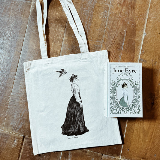 Bolsa de tela cruda con una mujer gata vestida de época y una golondrina sobrevolando su cabeza junto al libro Jane Eyre, de Charlotte Brontë ilustrado por Laura Agustí
