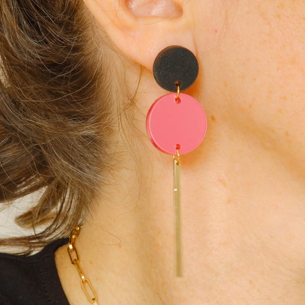 Mujer con unos pendientes de mitumi inspirados en Brigitte Bardot con dos círculos de metacrilato y una barrita de metal dorado