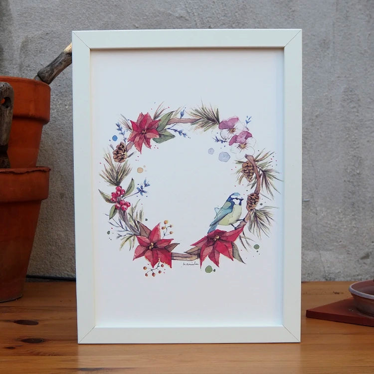 corona de flores invernales con de la artista Marialu con un pájaro posada sobre ella, y envuelta en un marco de color blanco
