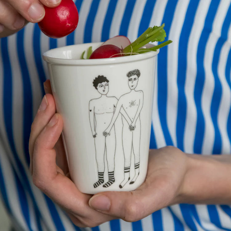taza de porcelana con el dibujo en negro de dos chicos desnudos y con las manos tapando los genitales del otro