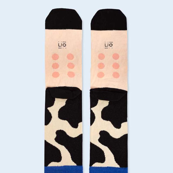 Calcetines eres la leche con diseño de piel de vaca en color crema y negro vista de la planta con ubres