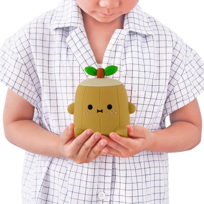 lamparita de noche quitamiedos con forma de árbol Ricelogi, con un tronco y una raa y dos hojitas encima sujetada por un niño de frente