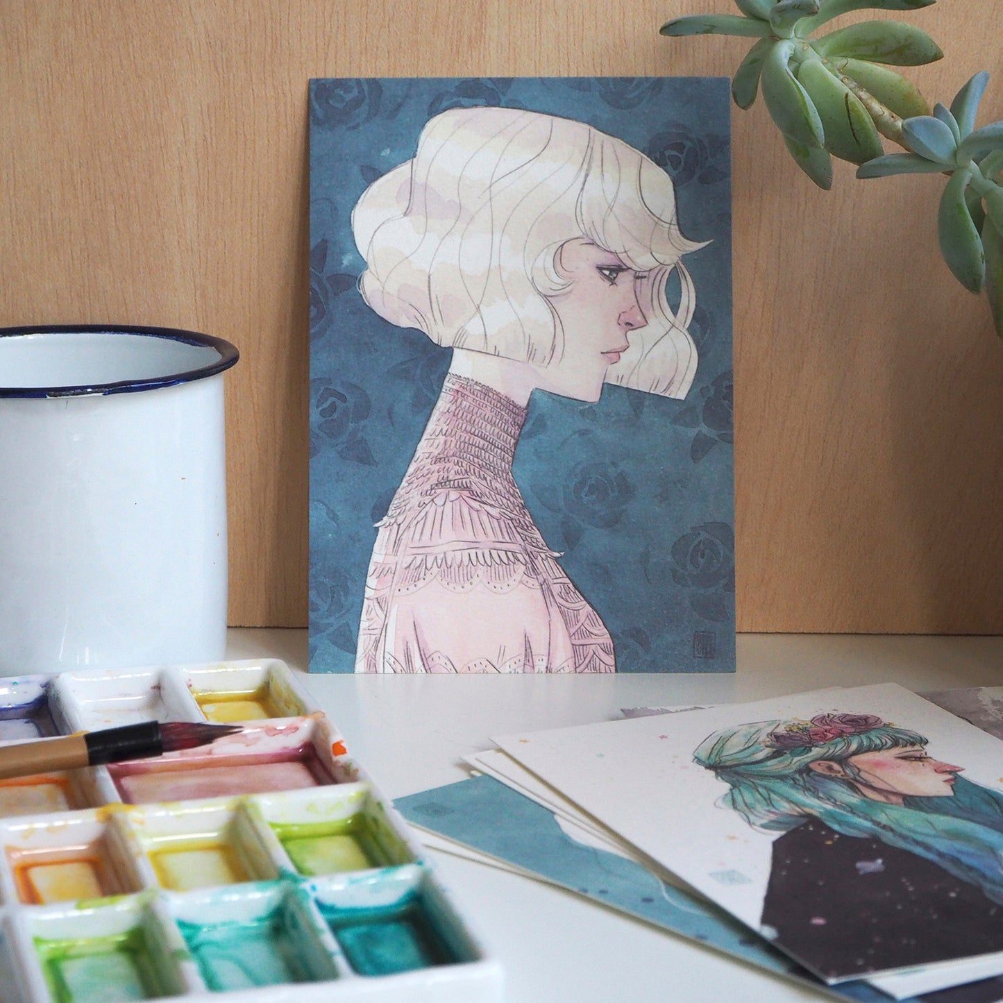 Postal con ilustración de Esther Gili de mujer de pelo blanco con cuello alto y fondo de papel pintado con rosas azules