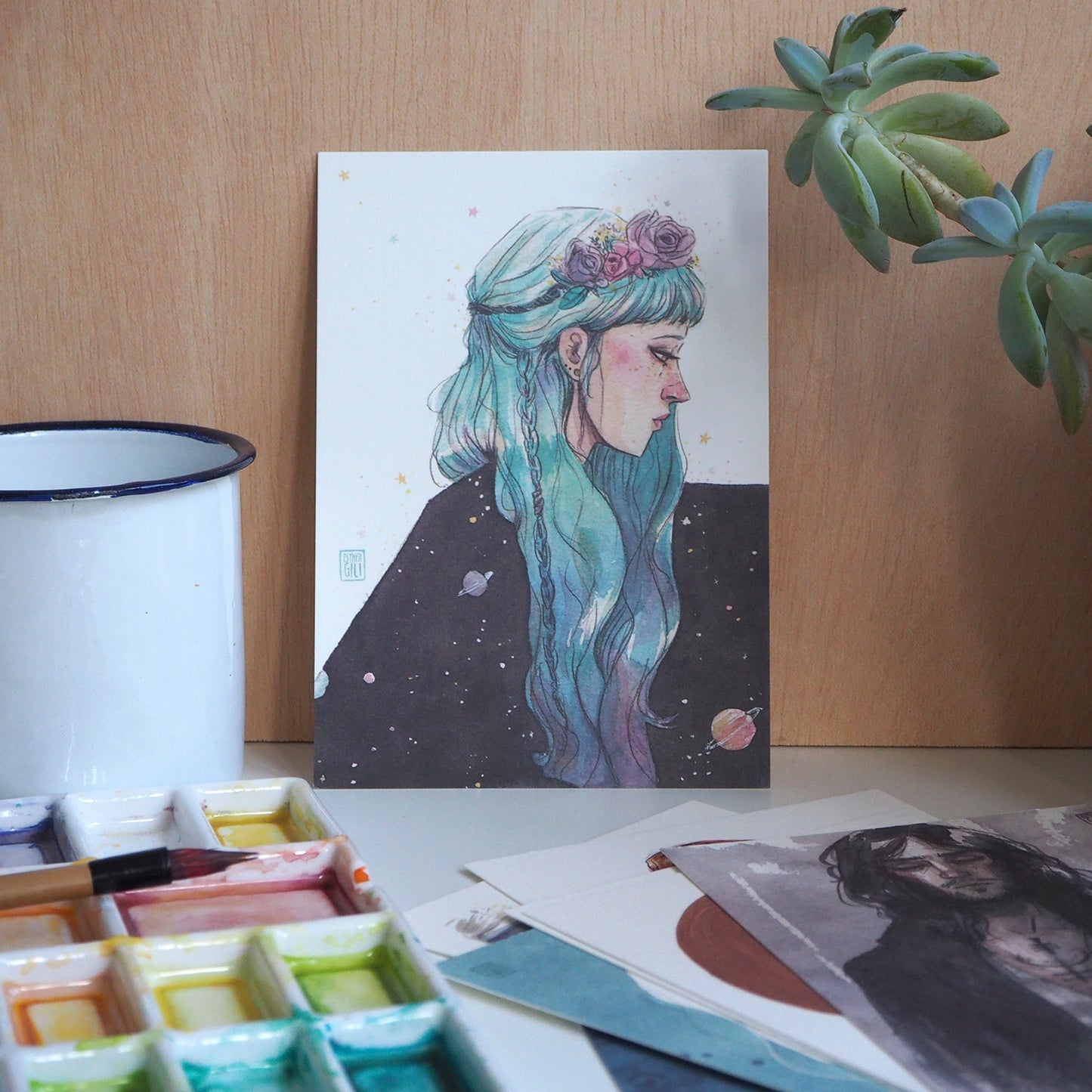 Postal de Esther Giili en la que una mujer de pelo azul con diadema de flores lleva un manto de la noche con planetas y estrellas