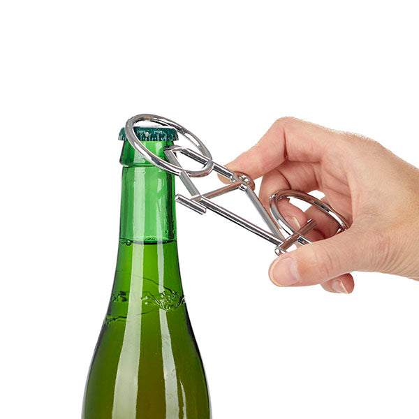 Mano abriendo un botellín con un abridor de metal con forma de bicicleta