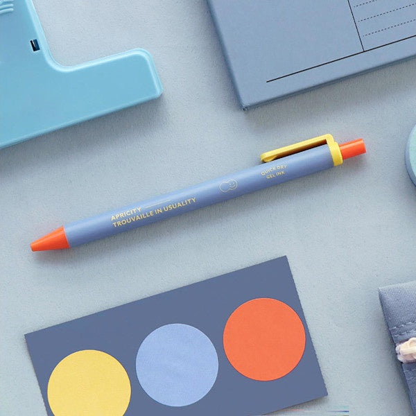 Bolígrafo de gel en azul lavanda, naranja y amarillo junto a material de papelería azul